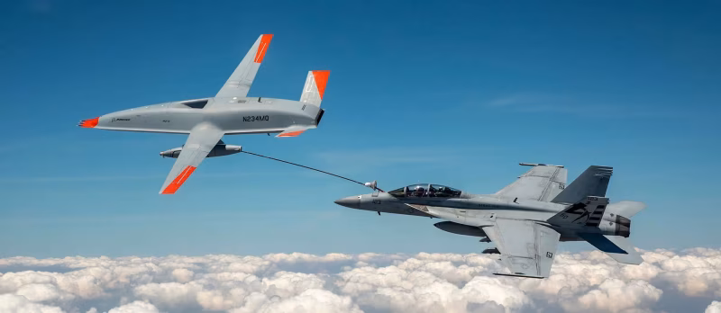 MQ-25 T1 test drone refueling an F/A-18 Super Hornet in flight above cloud cover