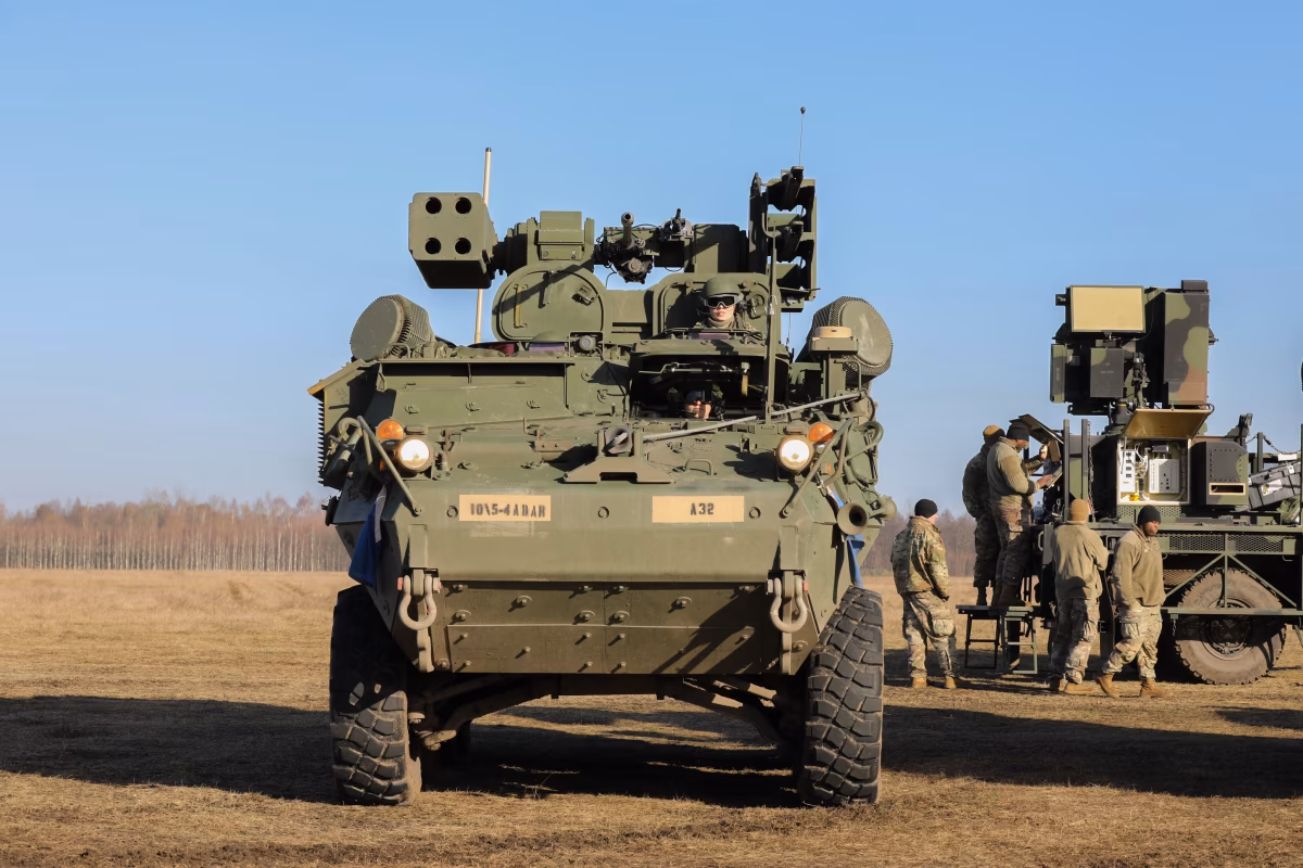 U.S. Army Stryker M-SHORAD air defense vehicle seen head-on during Saber Strike 2022 exercise in Poland, fitted with Stinger missile pods and radar systems, with soldiers operating additional air defense equipment in the background