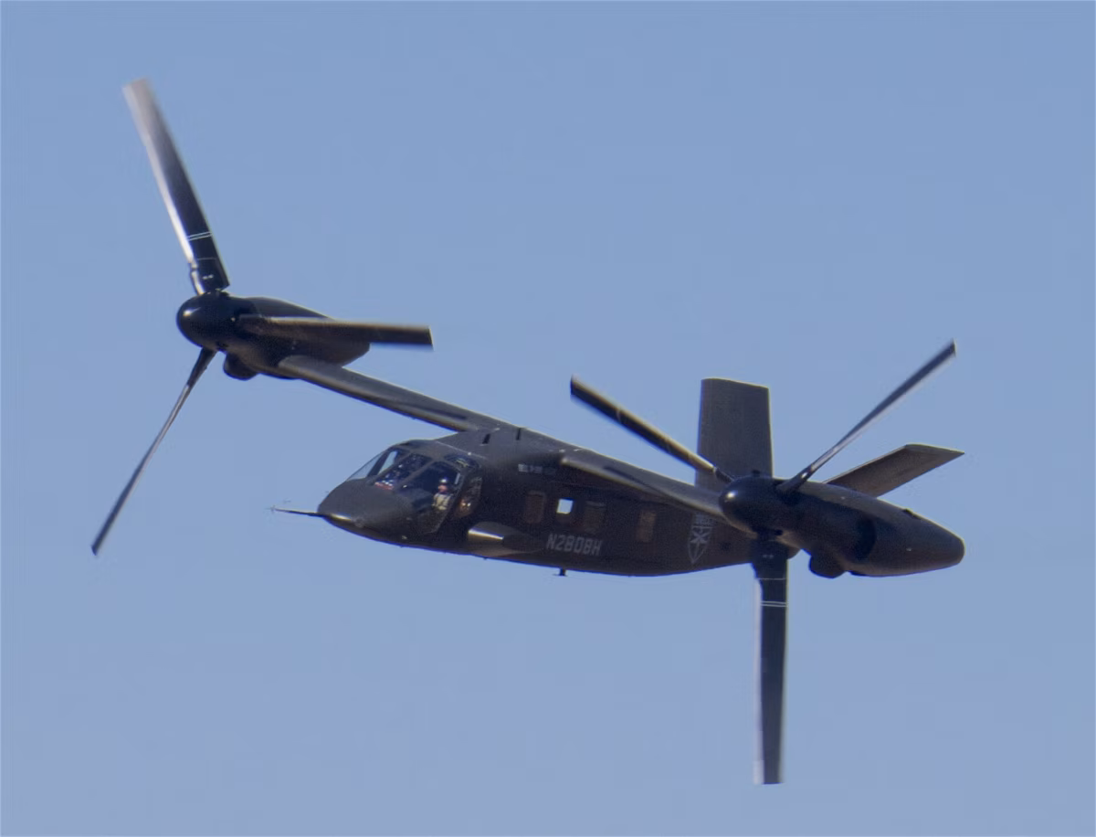 Bell V-280 Valor tiltrotor in high-speed cruise configuration, rotors tilted forward, in flight against a clear blue sky.