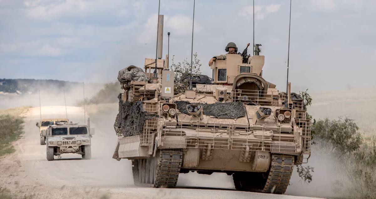 M2 Bradley IFV leading a convoy with multiple radio antennas visible, illustrating the communications equipment carried by networked armored formations.