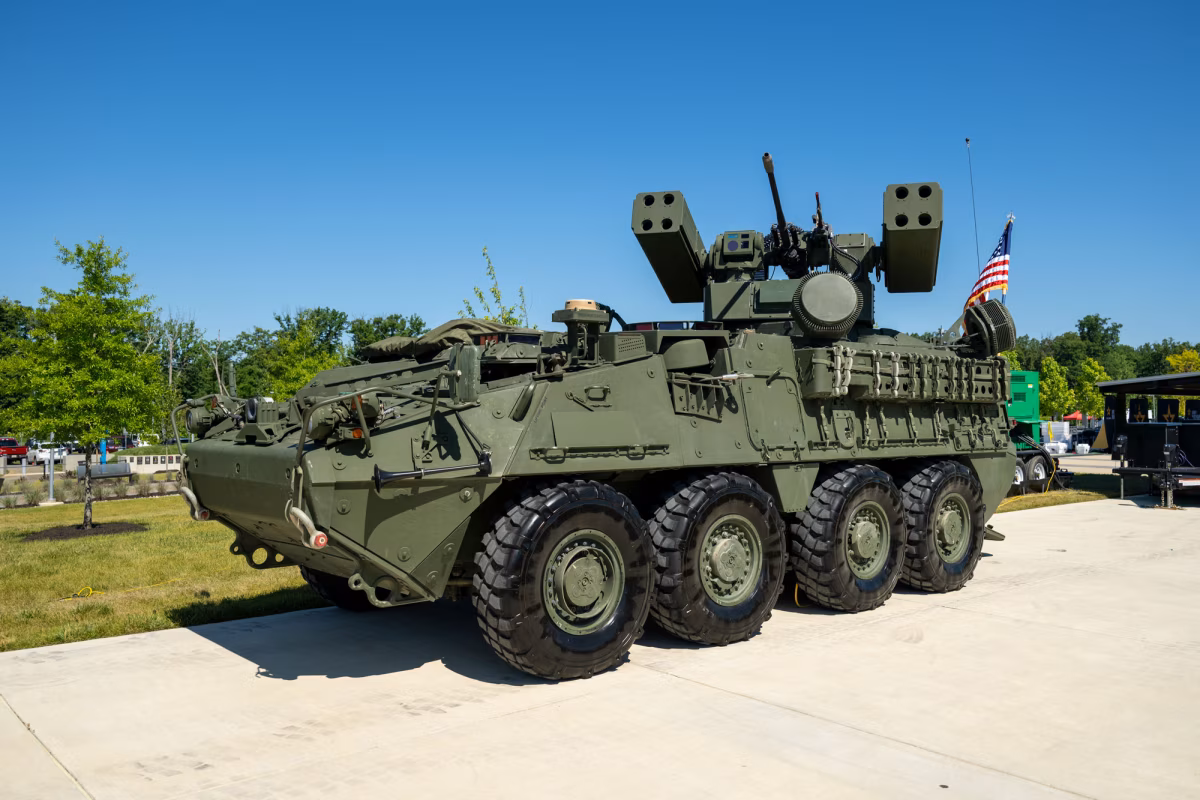 Stryker M-SHORAD air defense vehicle displayed at a U.S. Army static exhibition, showing the full 8x8 wheel configuration, dual Stinger missile pods, 30mm M230LF chain gun, and radar system mounted on the reconfigurable turret